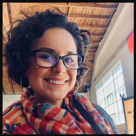 Picture of woman with short black hair wearing a colorful scarf and glasses. 